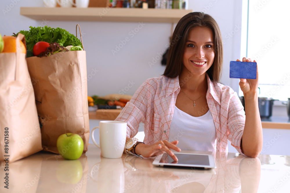 Smiling woman online shopping using tablet and credit card in