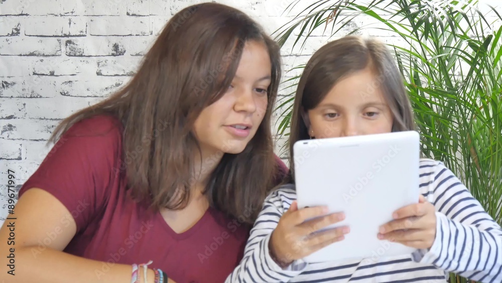 a girl and her sister playing with a tablet a girl and her sister playing with a tablet