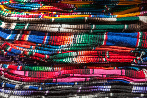 Colorful Mexican serapes hang in row.  