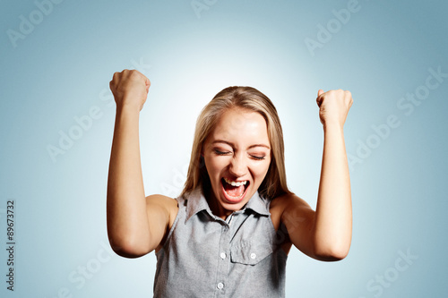 Pretty young blonde woman throwing her arms up into the air and