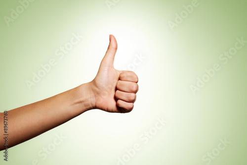 Woman hand with thumb up isolated on green background. Good sign