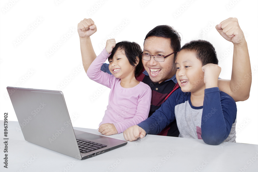Children and dad using laptop while raising hands Children and dad using laptop while raising hands