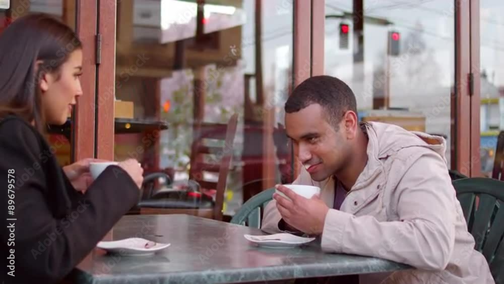 A young couple enjoying coffee outside of a downtown cafe A young couple enjoying coffee outside of a downtown cafe