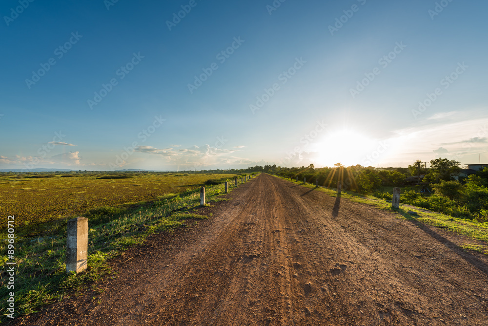 Rural dusty countryside road with sunset