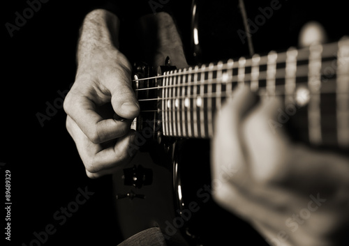  Hands of man playing guitar in dark colors