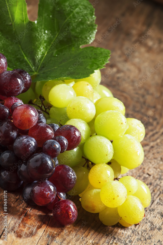 Green and purple round grapes on old wooden table, selective f Green and purple round grapes on old wooden table, selective f