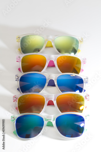 Many different colorful sunglasses in a row isolated on a white background