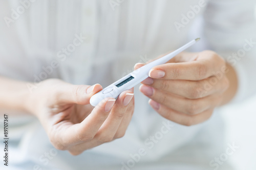 Woman looking at thermometer photo