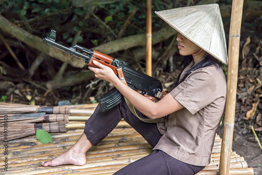 woman with a machine gun sits in a bamboo shelter woman with a machine gun sits in a bamboo shelter