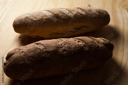 Due pagnotte di pane fatte a mano su un tagliere di legno .  photo