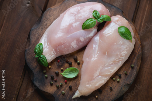 Cutting board with raw chicken breast fillet, top view, close-up