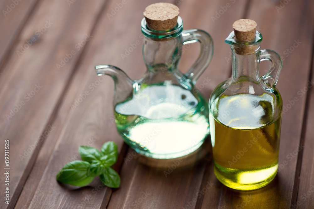 Olive oil in glass bottles and fresh green basil, studio shot Olive oil in glass bottles and fresh green basil, studio shot