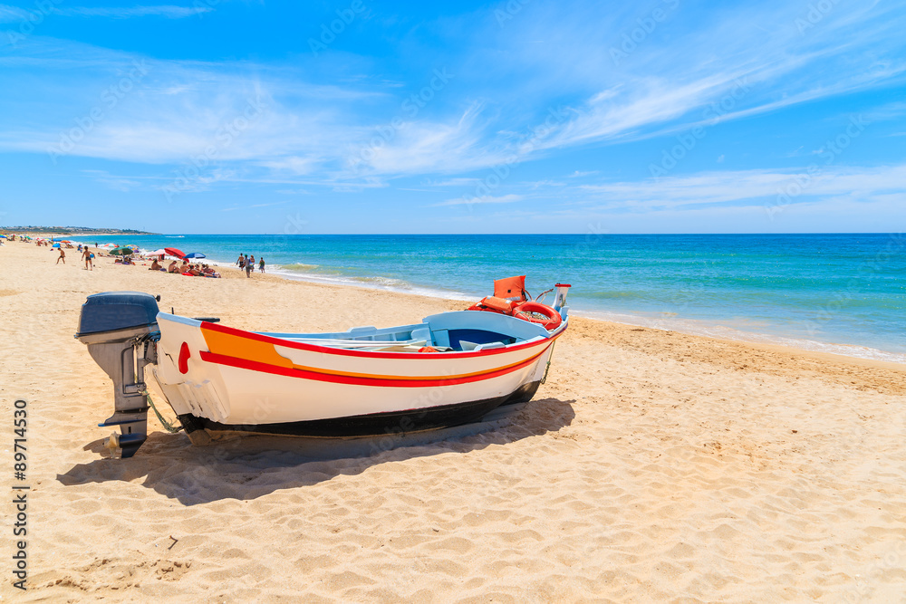 Typical colourful fishing boat on sandy beach in Armacao de Pera village, Algarve region, Portugal
