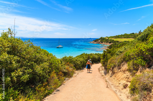Couple of tourists walking on path to beautiful beach in Grande Sperone bay, Corsica island, France
