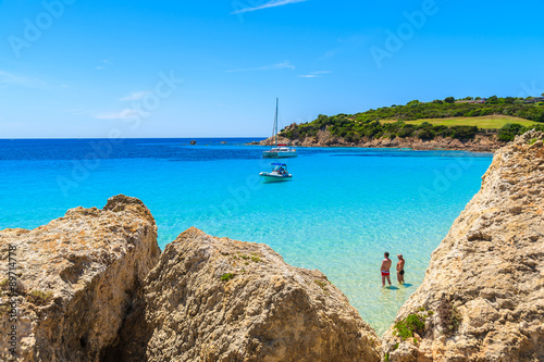 Two unidentified men standing in azure water of Grande Sperone bay and looking at sea, Corsica island, France