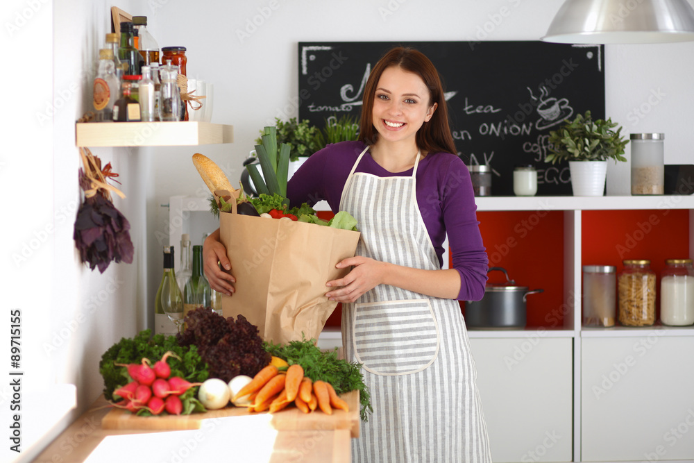 Young woman holding grocery shopping bag with vegetables