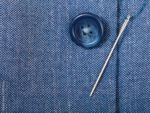 attaching of button to blue silk tissue by needle