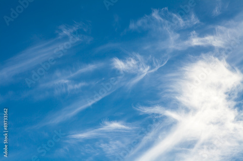 White cirrus clouds against a blue sky background