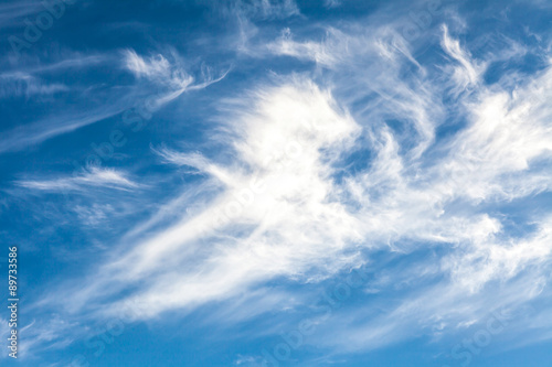 White cirrus clouds against a blue sky background