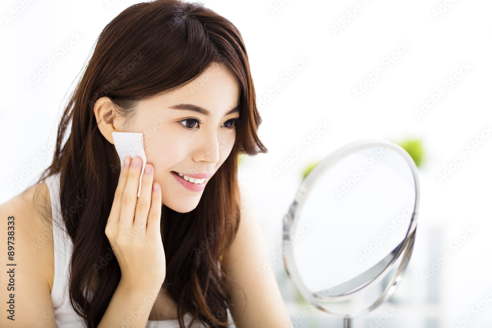 Beautiful young woman cleaning her face with cotton Beautiful young woman cleaning her face with cotton