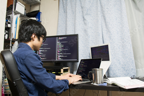 Plakat Asian engineer writing a programme on a computer