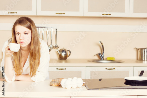 girl  white men's shirt with long flowing hair is drinking tea. kitchen. morning