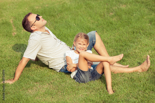 Father and daughter playing on the grass at the day time.