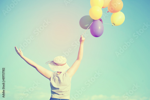 Vintage photo of young woman with colorful balloons in the summer field