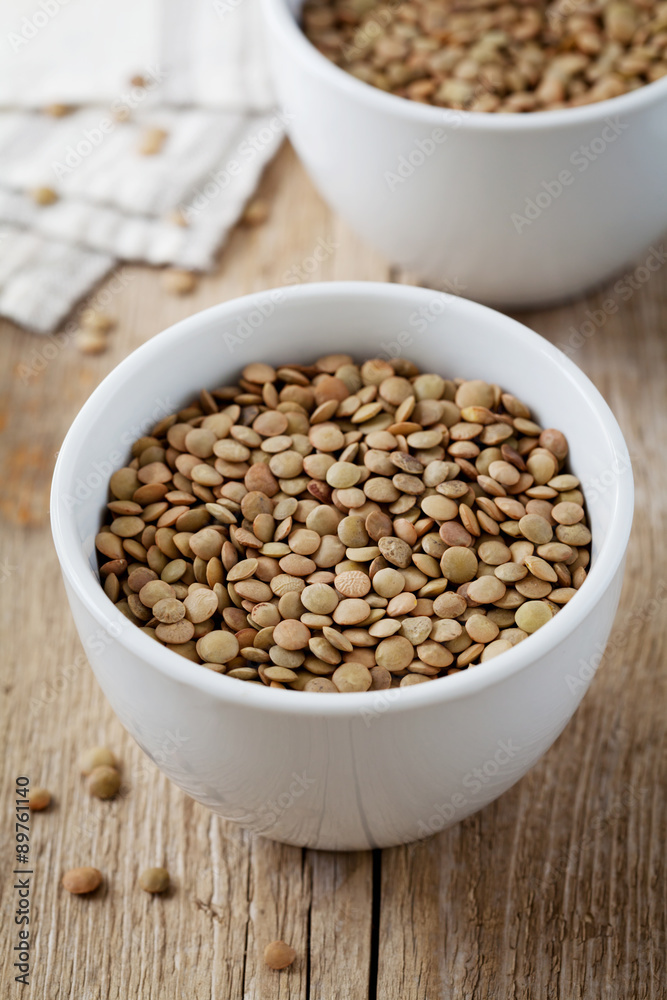 Bowl of dry lentils on a wooden background