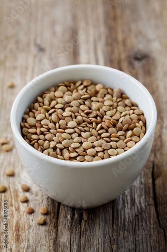 Bowl of dry lentils on a wooden background