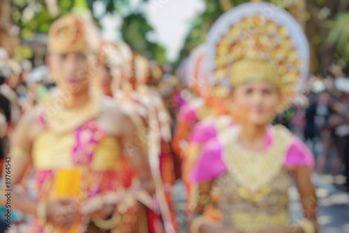 Wonderful Indonesia blur background. Bali people in beautiful Balinese costumes and hats with traditional style face make-up on cultural parade.