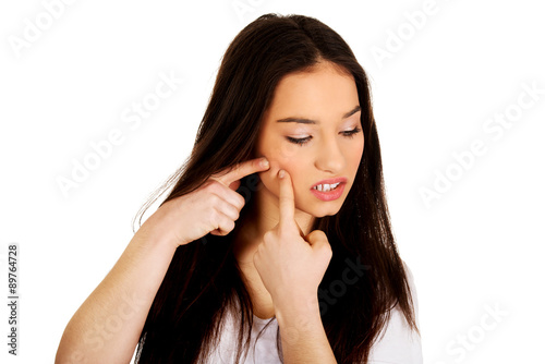 Teenage woman squeezing pimple.