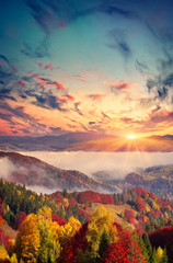 Colorful autumn sunset in the foggy mountains.