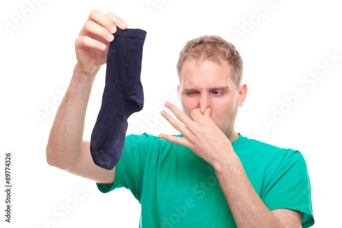 Man holding smelly socks and clogged nose