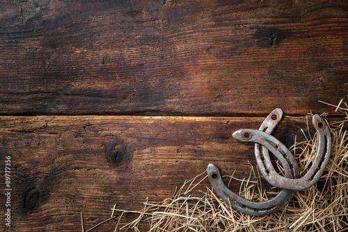 Two old rusty horseshoes with straw on vintage wooden board © Alexander Raths