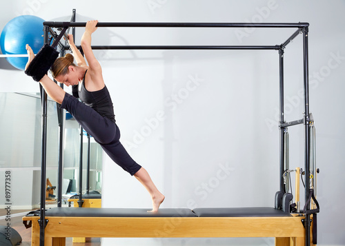 Pilates woman in cadillac split legs stretch exercise