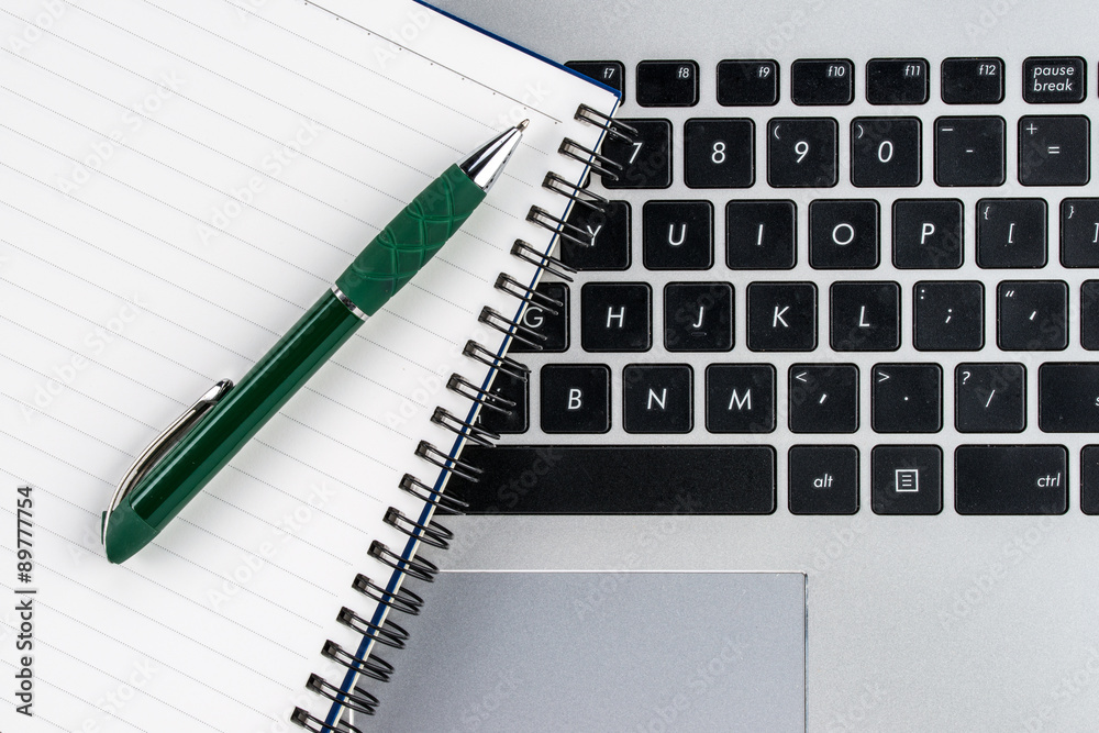 notebook and pen on the laptop keyboard, close up