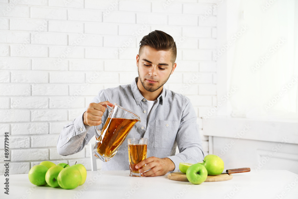 Fototapeta premium Young man man pouring apple juice into glass