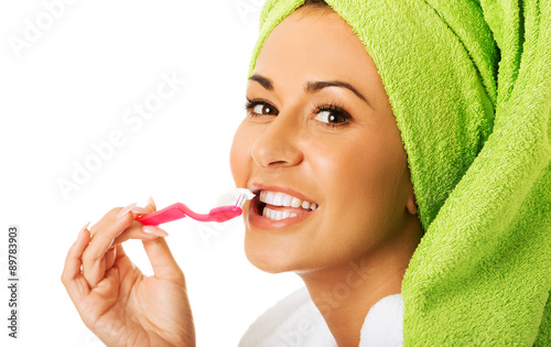 Woman in bathrobe brushing teeth