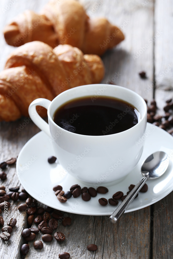 Delicious croissants with cup of coffee on grey wooden backgroun Delicious croissants with cup of coffee on grey wooden backgroun