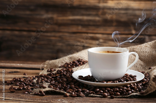 Cup of coffee with coffee beans on a brown wooden background photo