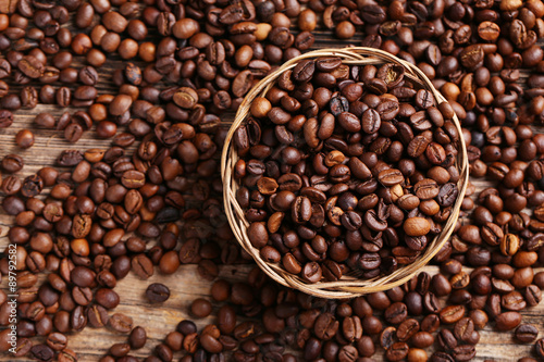 Roasted coffee beans in basket on a brown wooden background