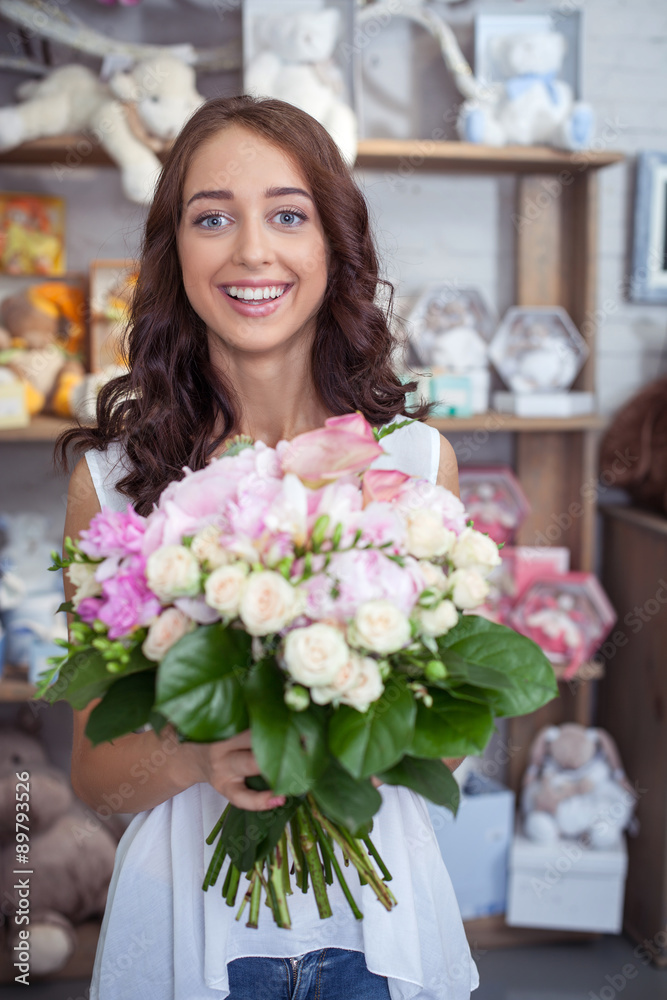 Cheerful young woman is buying bouquet in flower shop