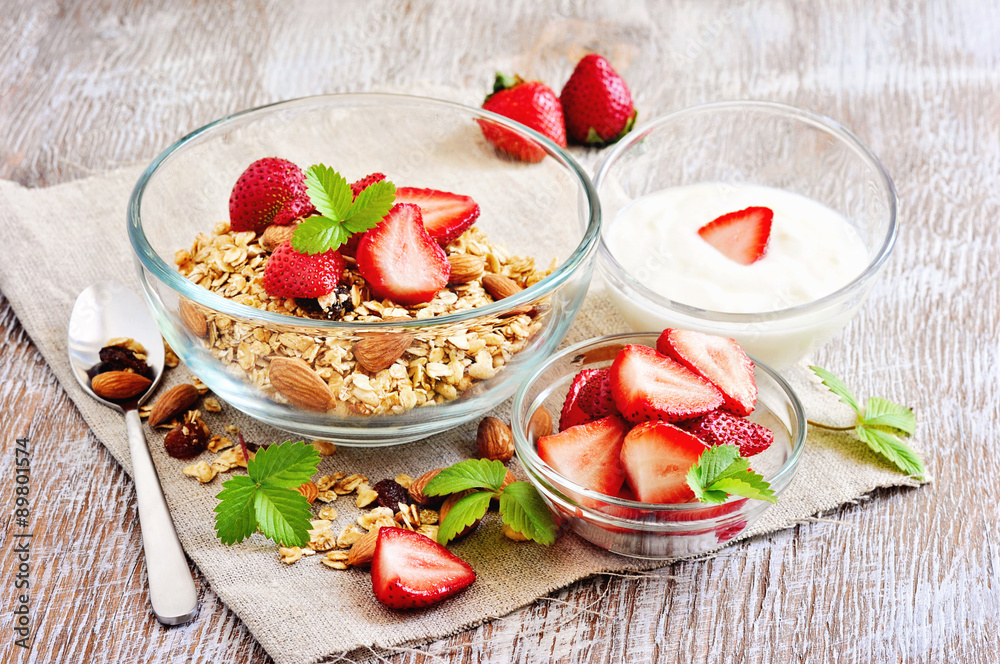Granola cereal with fresh strawberries, raisins, almonds, and yogurt, selective focus