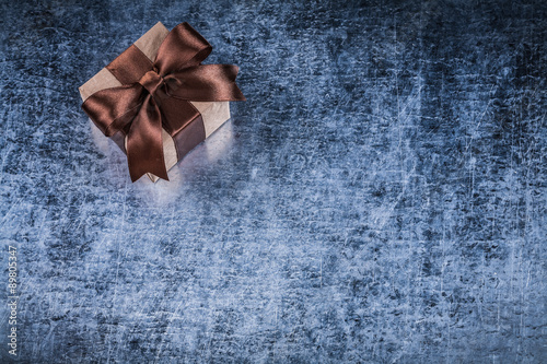 Giftbox with brown bow on scratched metallic background holidays © mihalec
