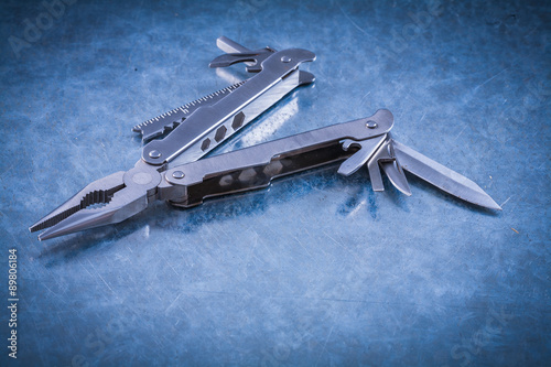 Multipurpose steel clasp-knife on scratched metallic surface photo