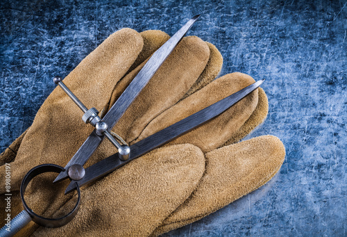 Pair of construction compasses safety gloves on scratched metall photo