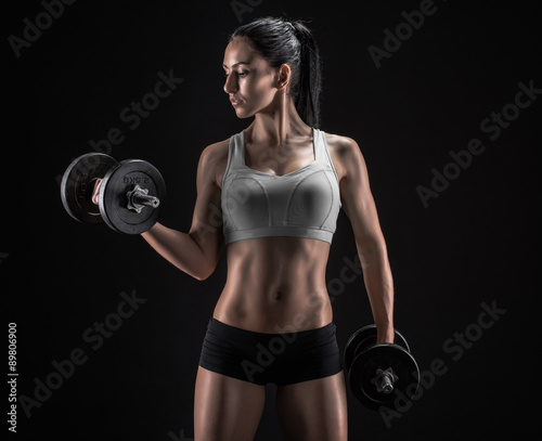 Young woman lifting the dumbbells