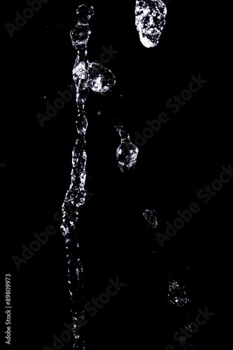 The large stream of water on a black background. Texture.
