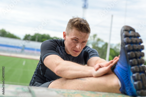 Close up shot of young male sprinter stretching on the before a © chettythomas